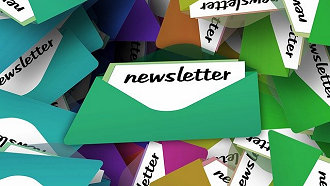 Green and other colorful envelopes laying in a pile with newsletter written on them