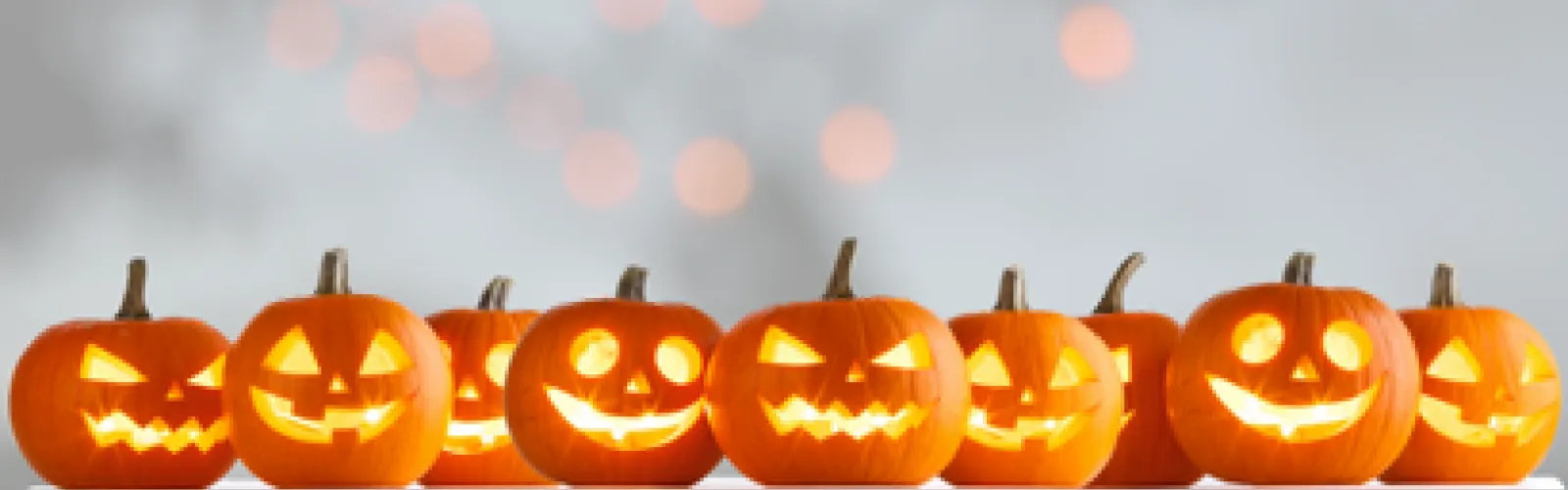 Carved and lit jack o lanterns on a gray background