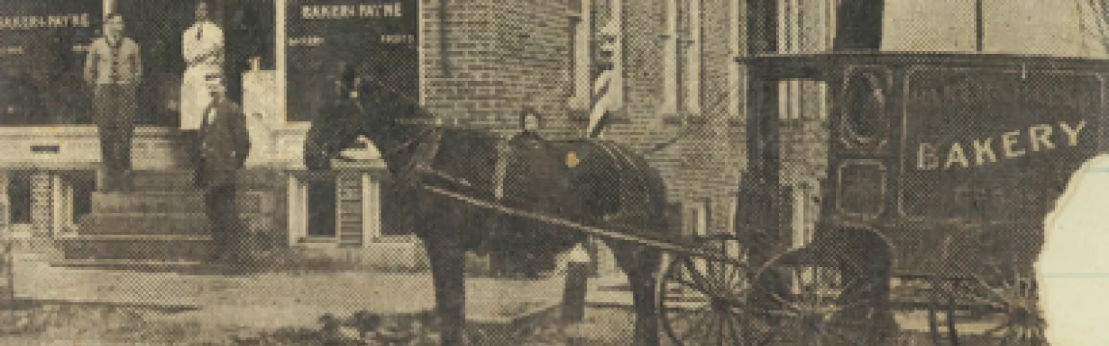 vintage photo on Main St. with horse pulling a bakery wagon and male and female onlookers watching from storefront stairs